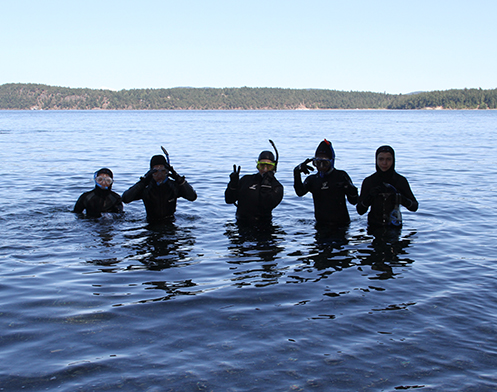 A group of five snorkelers standing in the bay for a picture 