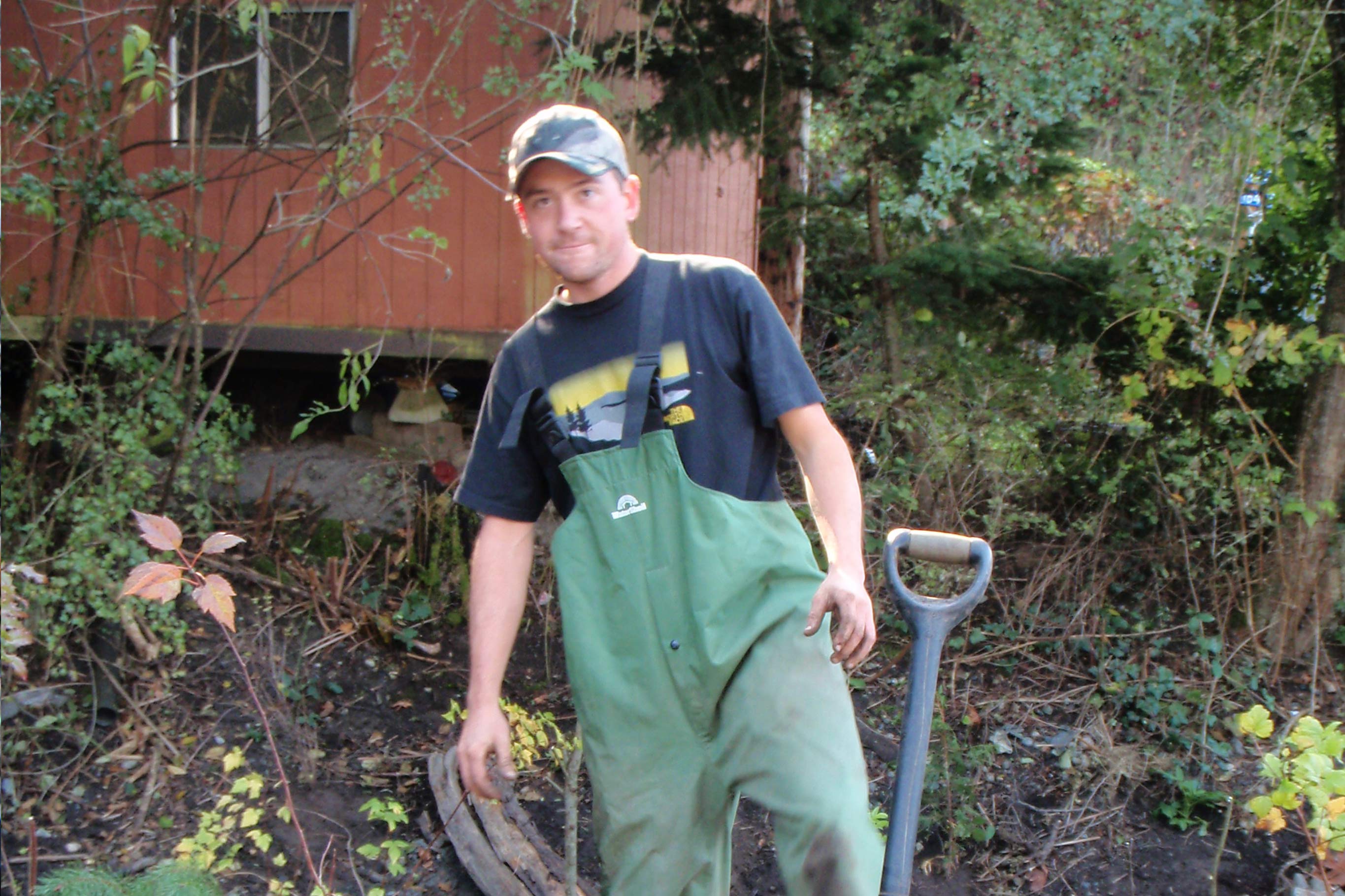 Aman in green overalls works the ground and is planting trees to restore nature back to its natural state